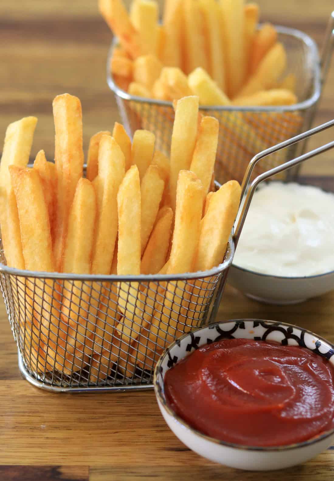 Golden fries served in a basket with dipping sauces